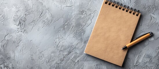 Poster - Spiral notepad and pen resting on a gray surface with copy space image nearby