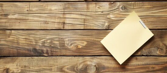 Fototapete - View from above of a wooden desk in an office workplace with a blank sticky note set against a backdrop suitable for copy space image