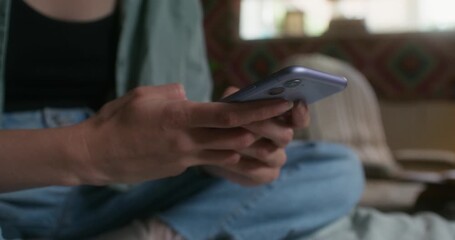 a woman sends text messages on a mobile phone sitting indoors. close-up of her hands, an unrecogniza