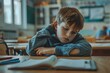 © Raool - Tired and bored boy sitting at desk in classroom at school, writing in notebook and thinking, resting head on hand, Generative AI