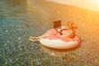 © svetograph - Woman laptop sea. Freelancer woman in sunglases floating on an inflatable big pink donut with a laptop in the sea. People summer vacation rest lifestyle concept