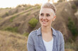 © Marharyta - Portrait of happy young woman with short haircut hairstyle wearing blue shirt in nature outdoors on sunset near green hills