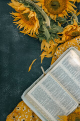 Wall Mural - Bible and sunflowers top view on black background