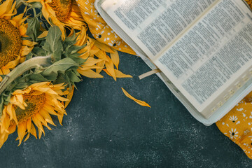 Wall Mural - Bible and sunflowers top view on black background