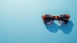 © sa-photo - A stylish pair of sunglasses on a light blue background, perfect for summer and travel promotions.