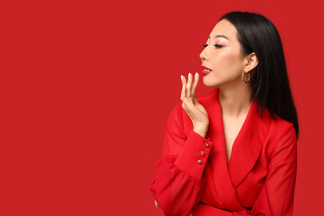 Wall Mural - Beautiful Asian woman with stylish makeup on red background