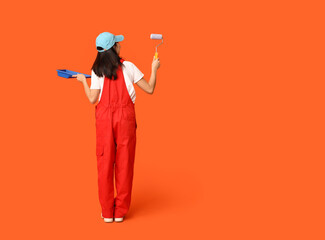 Wall Mural - female asian painter with roller and tray on orange background, back view