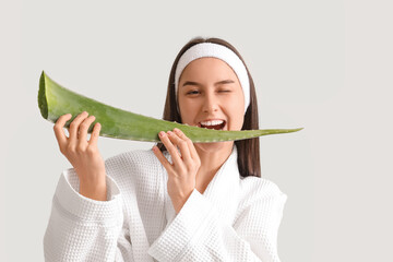 Wall Mural - Beautiful young happy woman in bathrobe with aloe vera leaf on white background