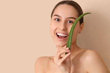 Wall Mural - Beautiful young happy woman with aloe vera on beige background