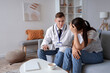 © Pixel-Shot - Male doctor comforting ill young woman at home