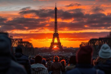 A large crowd gathers to gaze at the Eiffel Tower as it stands magnificently against a vibrant sunset sky, creating a scene that evokes awe, romance, and artistic inspiration.