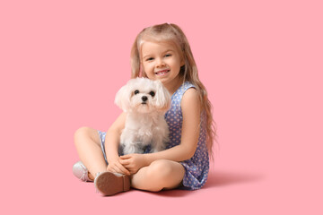 Wall Mural - Cute little girl with Maltese dog sitting on pink background