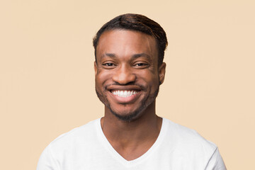 Wall Mural - Portrait Of Cheerful Black Guy In White T-Shirt Smiling To Camera Standing Over Yellow Background. Studio Shot