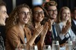 © Yuliia - Beautiful individuals wearing eyeglasses looking confidently at the panel of corporate recruitment officers, smiling and laughing as they applaud during a professional job interview.