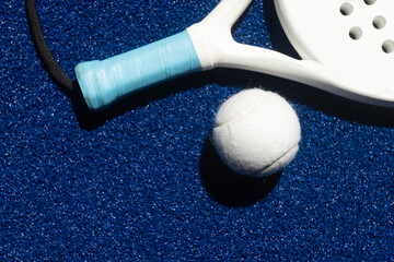 Wall Mural - White professional paddle tennis racket and white ball with natural lighting on blue background. Horizontal sport theme poster, greeting cards, headers, website and app