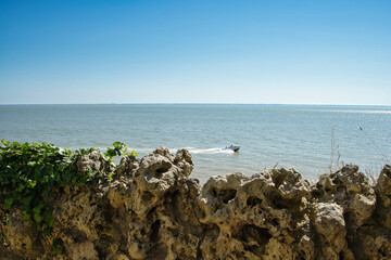 Boat under blue sky in the Atlantic Ocean in France with wall in the foreground