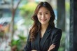 © darshika - Happy Asian businesswoman smiling with crossed arms.