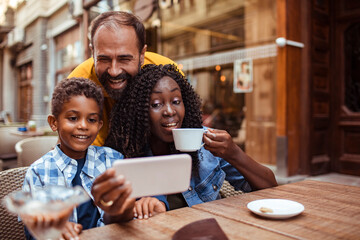 Wall Mural - Happy family taking a selfie at a sidewalk cafe