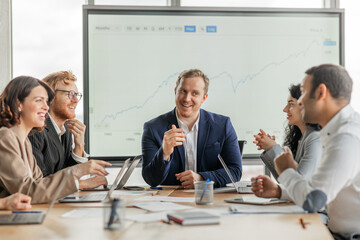 Aufkleber - A group of business professionals are gathered around a conference table in a modern office. The group is engaged in a conversation and appears to be working together on a project