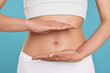 © New Africa - Healthy digestion. Woman holding something near her belly on light blue background, closeup