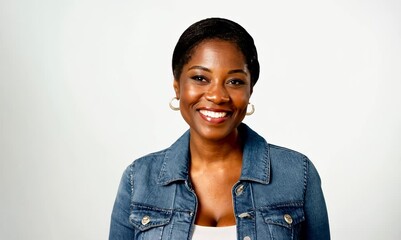 Wall Mural - portrait of a happy Kenyan woman in her 40s wearing a denim jacket against a white background