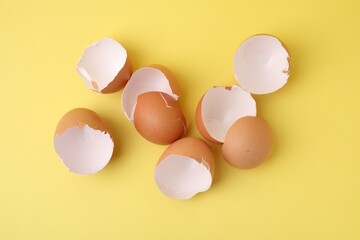 Wall Mural - Pile of broken eggshells on yellow background, top view