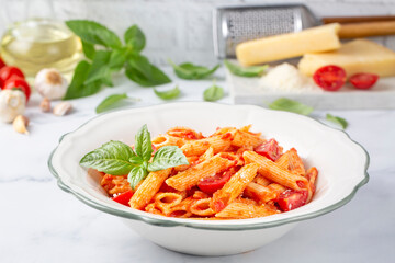 Wall Mural - Classic italian pasta penne alla arrabiata with basil and freshly grated parmesan cheese on dark table. Penne pasta with chili sauce arrabbiata.