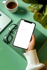 Wall Mural - A person holding a phone with a white screen on a green table