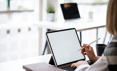 Wall Mural - mockup image of a woman holding stylus pen and using digital tablet with blank white desktop screen 