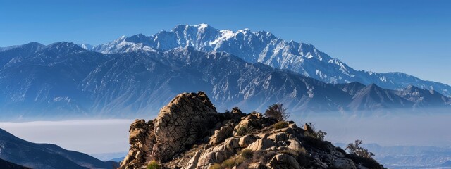 Wall Mural -  A panorama of mountain ranges from a rocky outcropping's peak, featuring low-lying clouds in the foreground