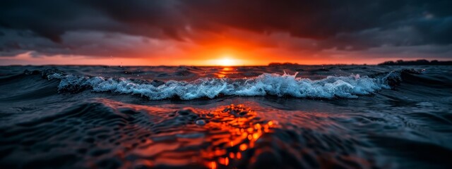 Canvas Print -  A sunset over a body of water with a foreground wave and background dark clouds