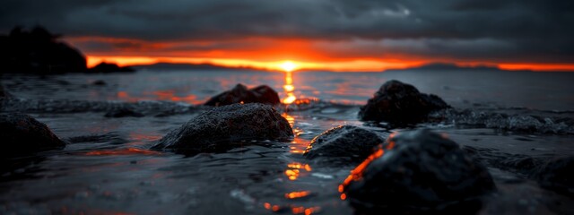 Canvas Print -  A sunset over a body of water with rocks in the foreground and a water expanse as the backdrop