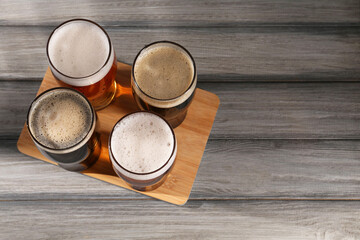 Canvas Print - Glasses with different types of beer on grey wooden table, top view. Space for text