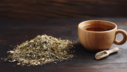 Wooden cup of natural tea and heap of dried herbs on wood table. Tasty and healthy drink.