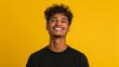 © Trushchenko_O - A man with a black shirt and curly hair is smiling at the camera. The image has a bright and cheerful mood, as the man's smile and the yellow background create a positive atmosphere