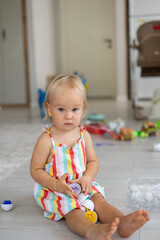 A beautiful blonde baby girl playing with a plastic montessori eggs