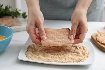 Wall Mural - Woman making schnitzel at white table, closeup