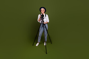 Sticker - Full length photo of charming positive camerawoman wear white shirt hat tacking photo empty space isolated green color background