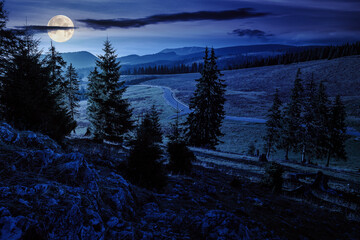 Wall Mural - autumn mountain landscape at night. asphalt road winds through mountains and passes the meadow near 