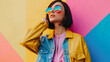 © VK Studio - A stylish woman in colorful glasses and a bright jacket poses confidently against a vibrant, geometric-patterned wall.
