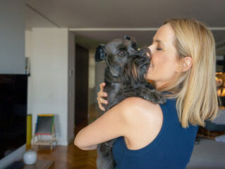 Wall Mural - Portrait of a Young blonde woman hugging dog at home