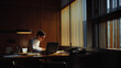 © VK Studio - A man works late in a warmly lit office, surrounded by books and papers, in an evening atmosphere with long shadows.