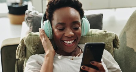 Canvas Print - Black woman, relax and phone with headphones on sofa for streaming music, listening audio and dancing at house. Happy, female person and mobile for social media, online video and subscription service