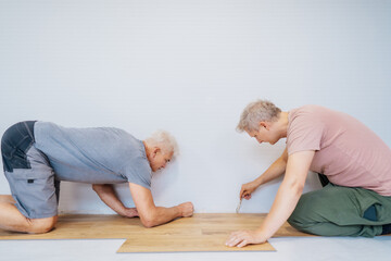 Wall Mural - Father and adult son installing flooring in new Home by their own. Doing measurements, calculating for vinyl laminate and skirting. DIY, Do it yourself. Home renovation, improvement, refurbishment