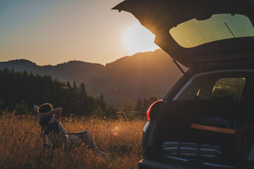 Wall Mural - Young beautiful woman traveler enjoying the sunset in the mountains while traveling