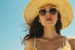 © Anat art - A woman dressed in a light summer outfit enjoys a sunny day at the beach, showcasing her sunglasses and wide-brimmed straw hat against a clear blue sky. Generative AI
