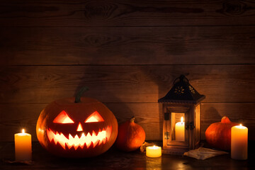 Wall Mural - Halloween pumpkin head jack lantern with burning candles on old wooden table.