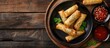 © meristock - A modern black plate with spring rolls and sweet chili sauce sits stylishly on a wooden table creating an enticing copy space image
