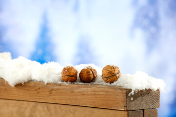 Wall Mural - Walnuts on wooden snow covered board with snowy winter background  