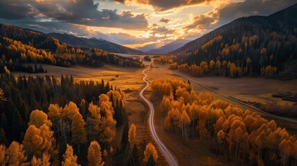 Wall Mural - A winding road passes through a serene mountain valley filled with vibrant autumn trees under a dramatic sunset sky, showcasing the peaceful beauty of nature.